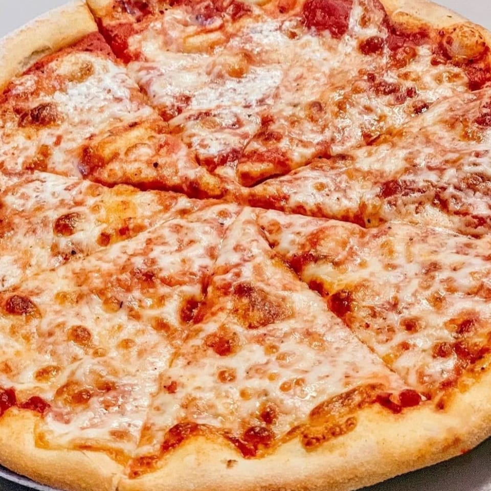 A freshly baked, sliced cheese pizza from Fig & Tomato, with melted mozzarella and red sauce.