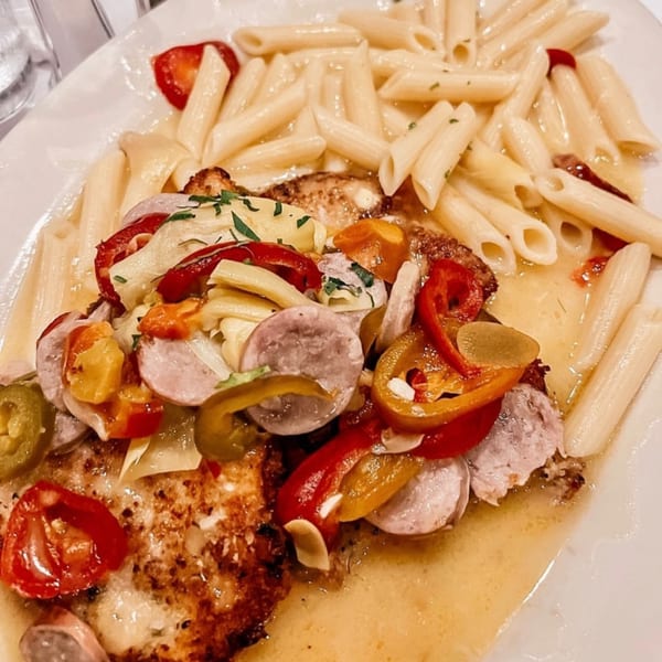 Italian dish with penne pasta, chicken, sausage, peppers, and tomatoes in a light sauce.