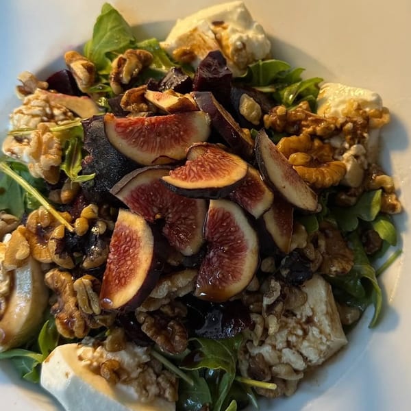 A vibrant Fig & Tomato salad with sliced figs, walnuts, goat cheese, and greens.