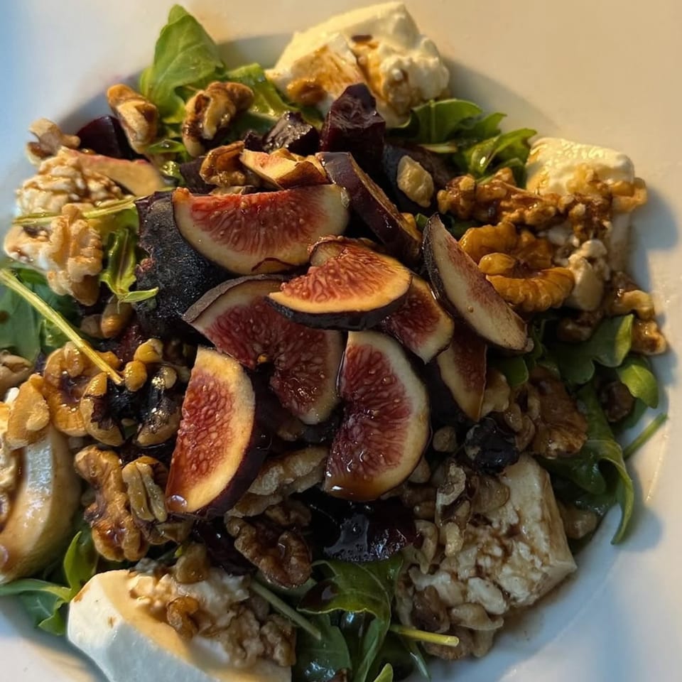 A vibrant Fig & Tomato salad with sliced figs, walnuts, goat cheese, and greens.