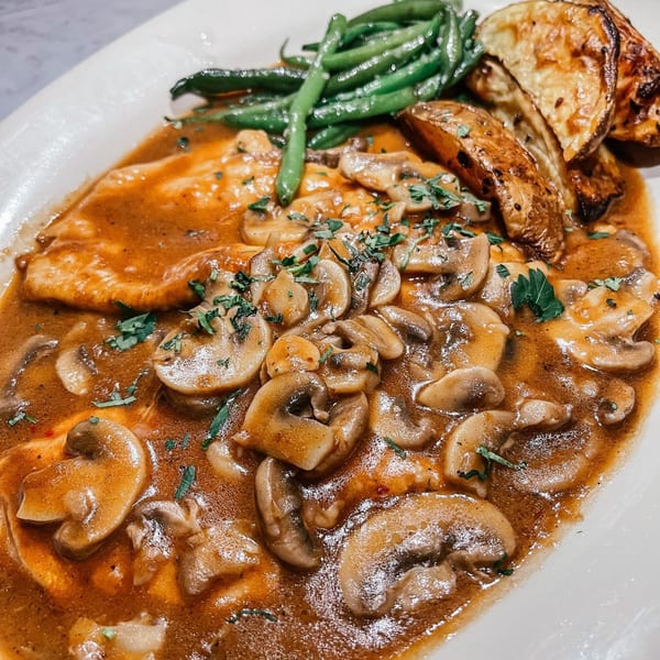 Chicken Marsala with mushrooms, green beans, and roasted potatoes on a white plate.