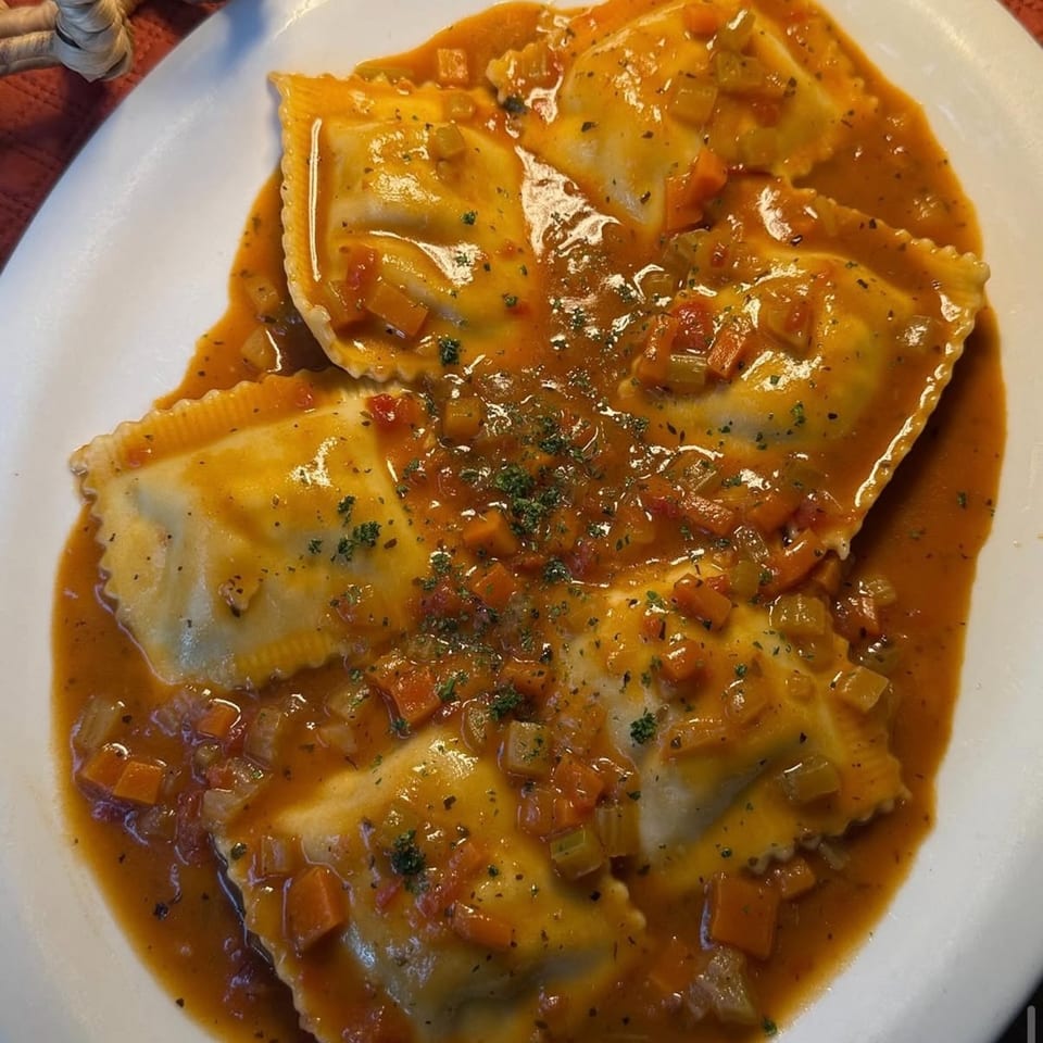 Fig & Tomato's ravioli pasta dish with a rich tomato sauce, diced vegetables, and herbs.