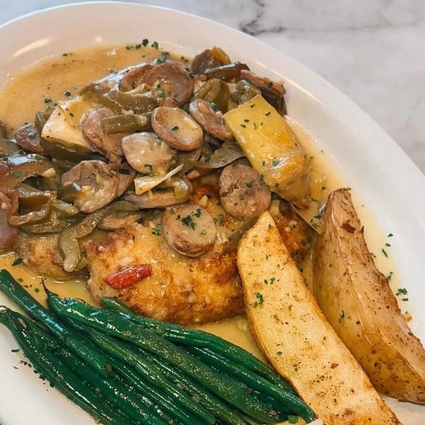 Italian dish with chicken, mushrooms, peppers, green beans, and potato wedges in a creamy sauce.