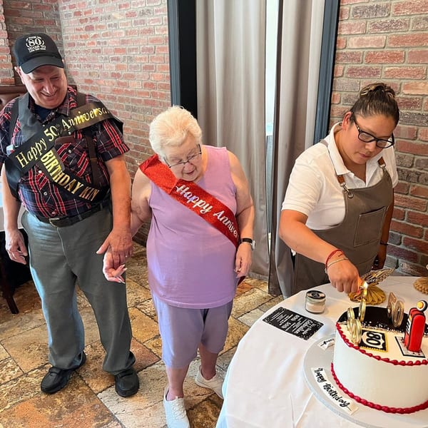 A couple celebrating their 80th birthday and 50th anniversary with a cake at Fig & Tomato.