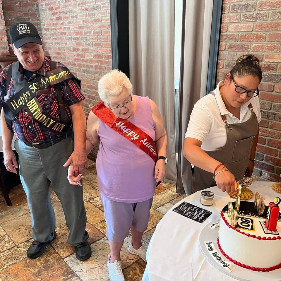 A couple celebrating their 80th birthday and 50th anniversary with a cake at Fig & Tomato.